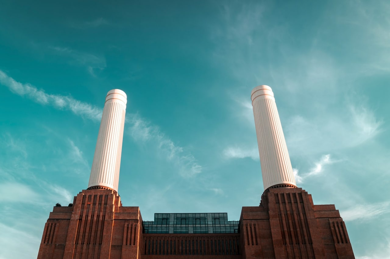 The four white chimneys of Battersea Power Station against a blue sky