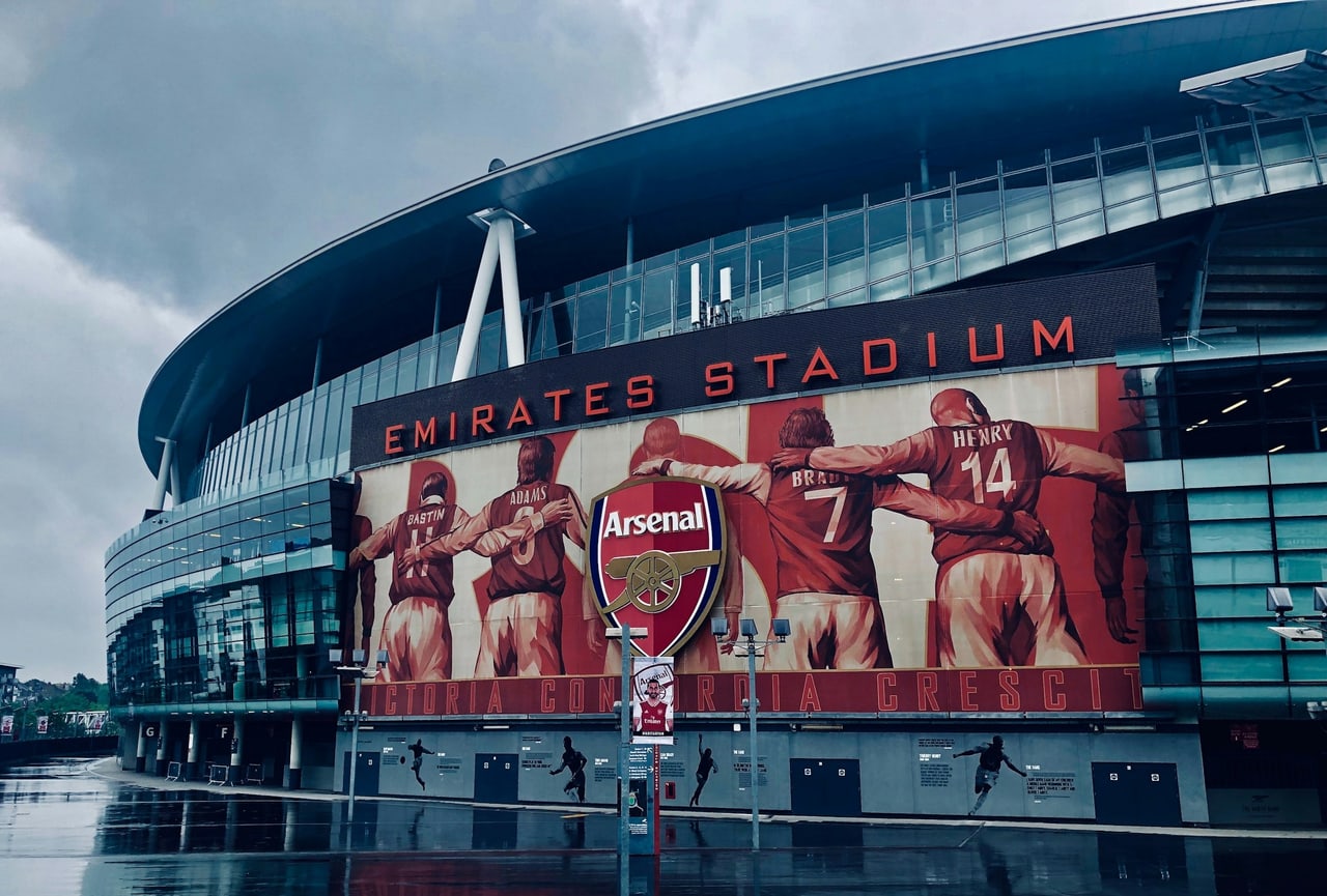 The Emirates Stadium with a large mural of Arsenal players along the exterior