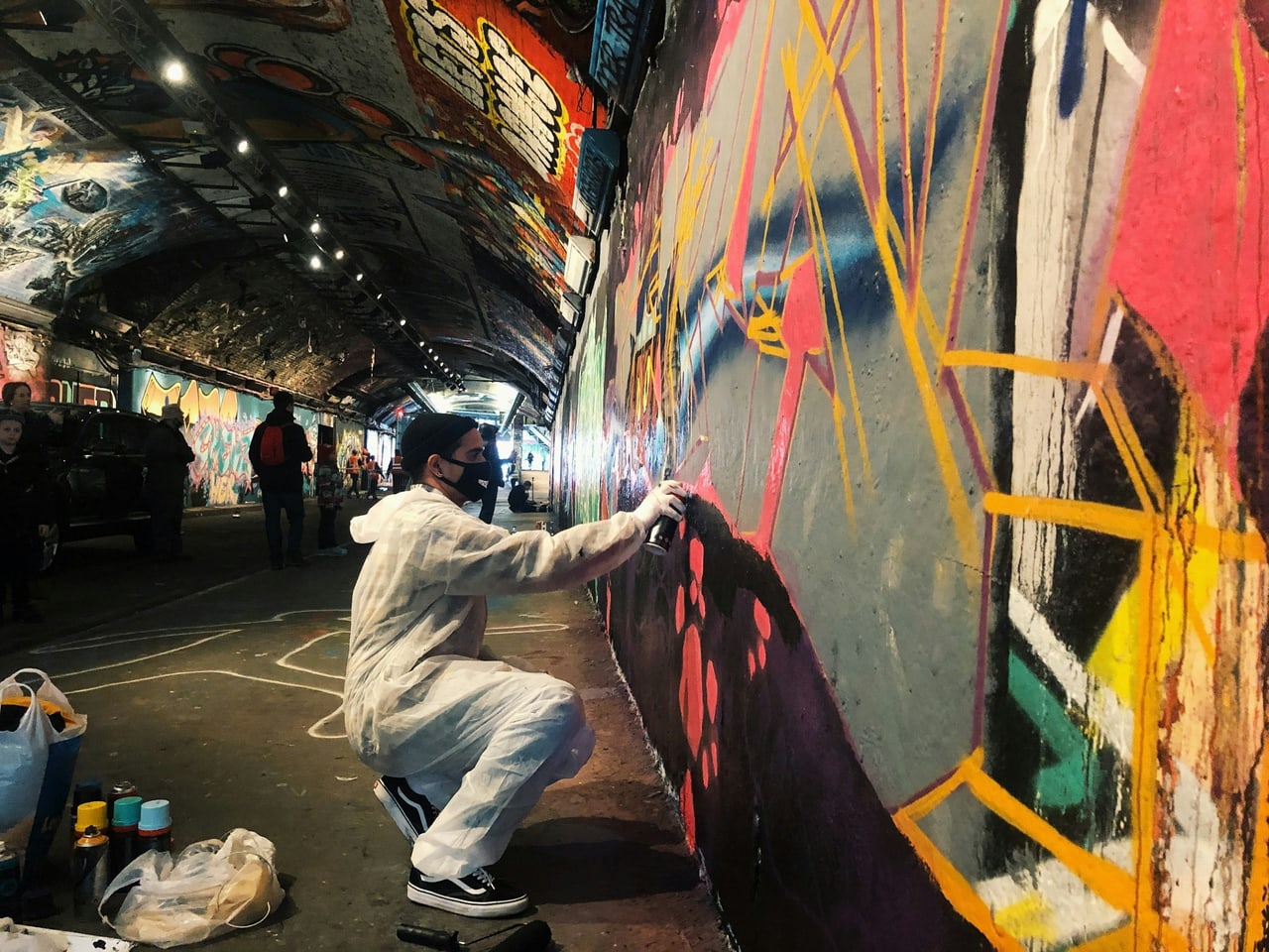 An artist spray-painting a wall inside the Leake Street graffiti tunnel under Waterloo station