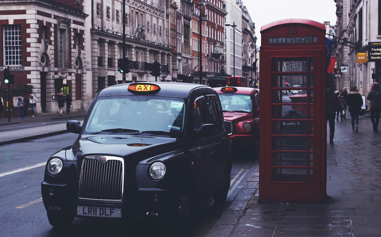 A London black taxi on a city street beside a red telephone box