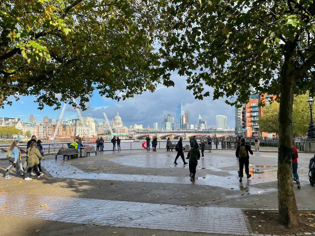 Walkers on the Thames path on the South Bank with the London skyline behind
